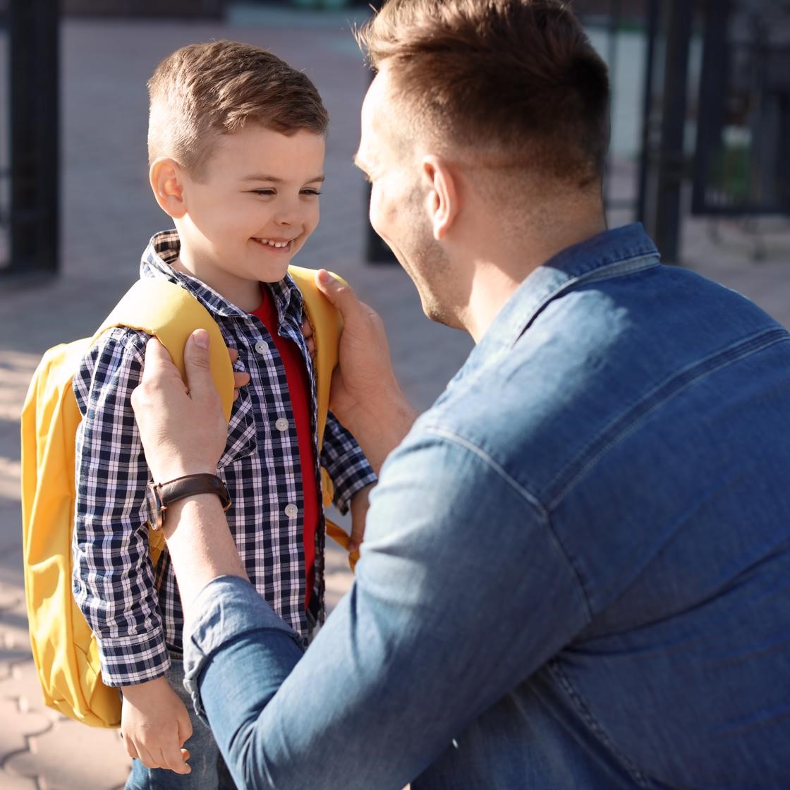 young boy and male caregiver embracing outside early learning centre