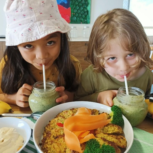 Two children enjoying spinach, banana and avocado smoothie